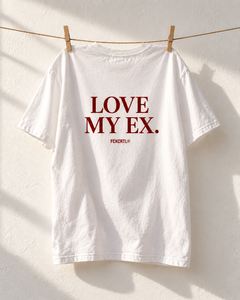 Back of Love My Ex white T-shirt hanging on a clothesline against an off-white wall
